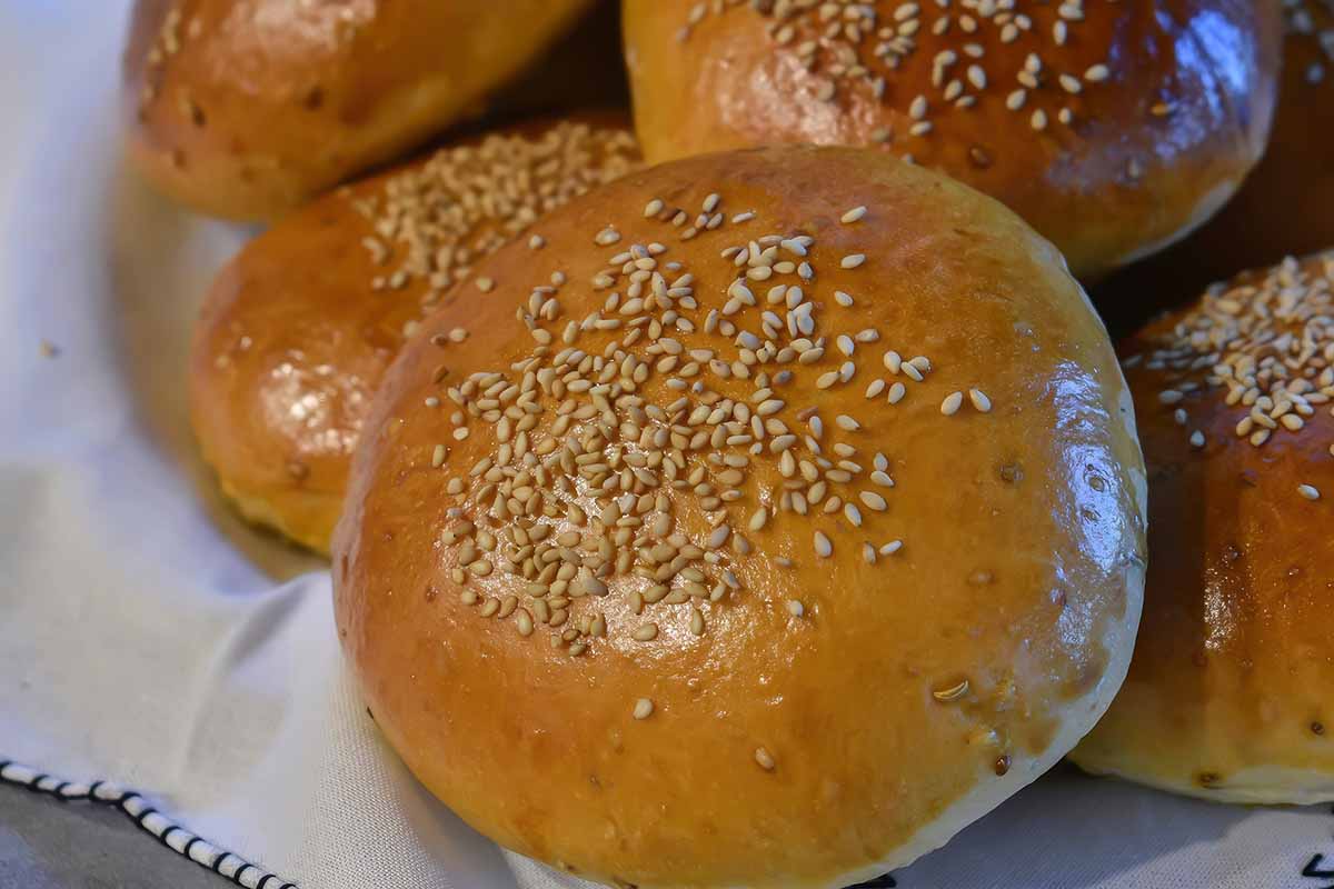 A close up horizontal image of buns sprinkled with anise seeds.