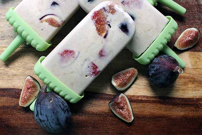 A close up horizontal image of fig banana popsicles on a wooden surface.