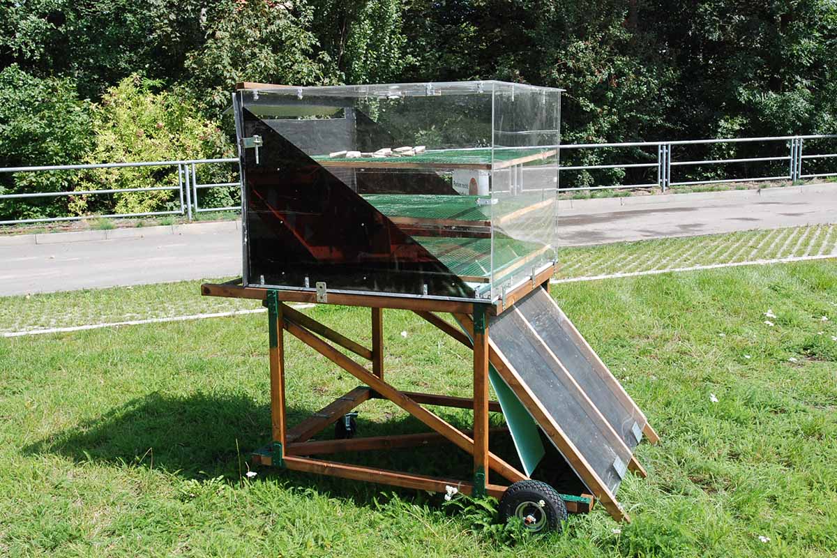 A horizontal image of a solar food dehydrator outdoors in the sun.