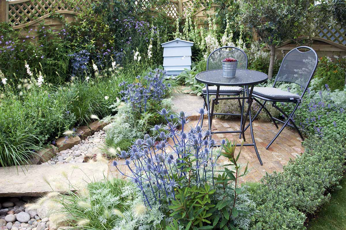 A horizontal image of a small outdoor seating area with blue and white flowers adorning the borders.