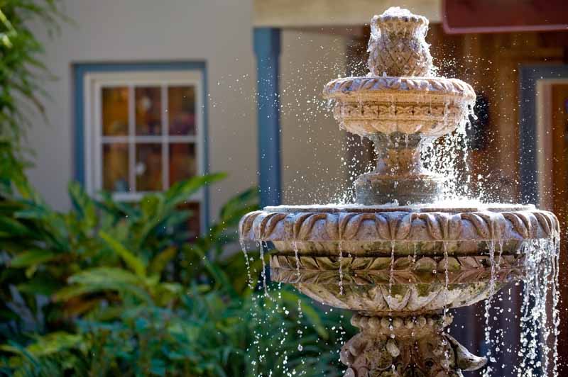A garden fountain in the front of a residence.
